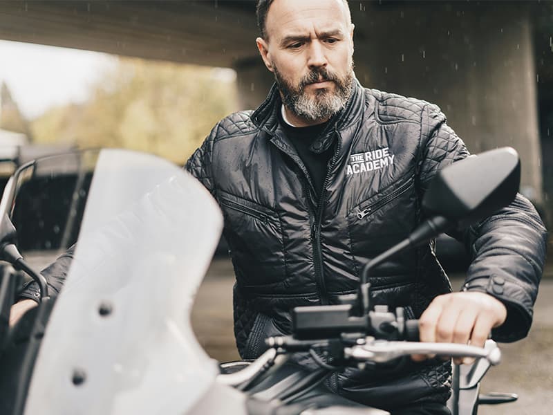 A white man parking his motorbike.