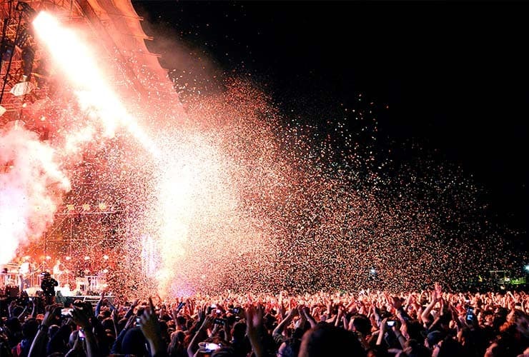 A crowd cheering a band at night Primavera Sound Festival with confetti in the air.
